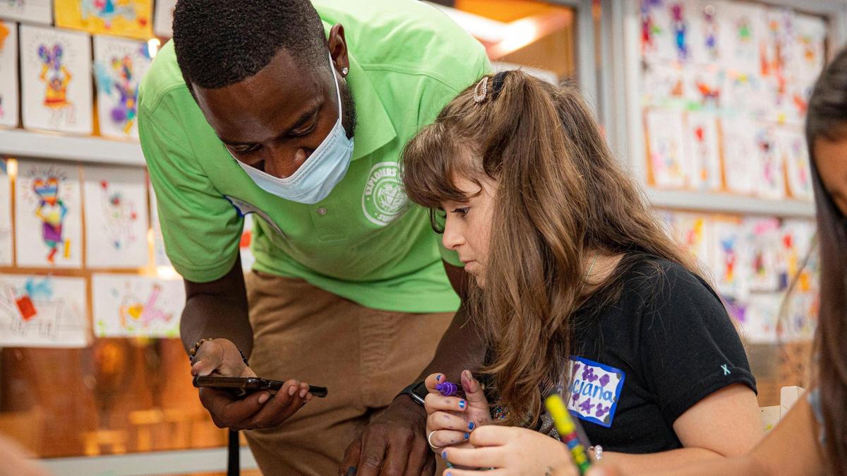 John Martin, left, assists Luciana Goncalves, 8, with decorating her wooden star for the Miami Children’s Museum’s Stars of Hope project in Miami on Tuesday, Jun.e14, 2022.
