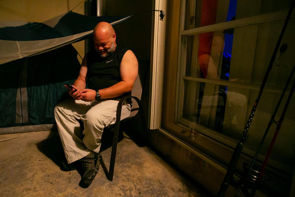 John Delgado, 52, checks his phone before before going to bed at his home in Homestead. He chats with his wife on video, his only link to life inside.