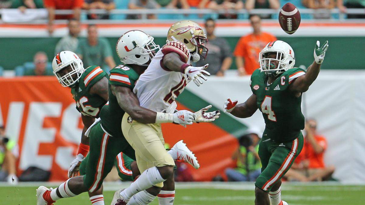 Miami Hurricanes cornerback Michael Jackson, shown tackling FSU’s Tamorrion Terry earlier this season, is aided by safety Jaquan Johnson as he battles for the loose ball. Both defensive backs are part of the outgoing UM senior class that will play in the 2018 regular-season finale Saturday against Pittsburgh.