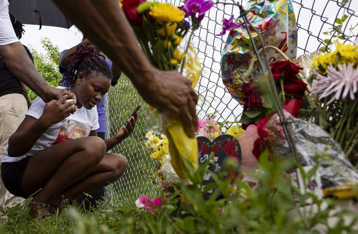 Lateisha Wilkinson places a lighted plastic candle at a makeshift memorial for her mother, Doreen Richards Broadbelt, 71, who police said was walking to her job at Walmart when a dog attacked and fatally mauled her near her home on Labor Day. A vigil was held nearby at Broadbelt's home on Tuesday, Sept. 9, 2025, in Miami Gardens, Fla.