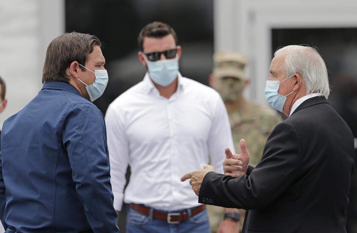 Florida Gov. Ron DeSantis talks to Miami-Dade County Mayor Carlos Gimenez after a press conference to announce COVID-19 antibody testing, a mobile lab, and a mask decontamination facility at Hard Rock Stadium on Wednesday, May 6, 2020.