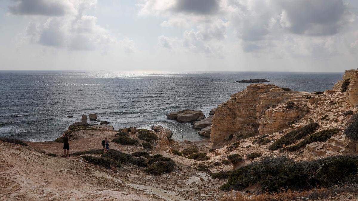 Tourists visit a beach near the town of Pegeia in western Cyprus on May 9, 2018