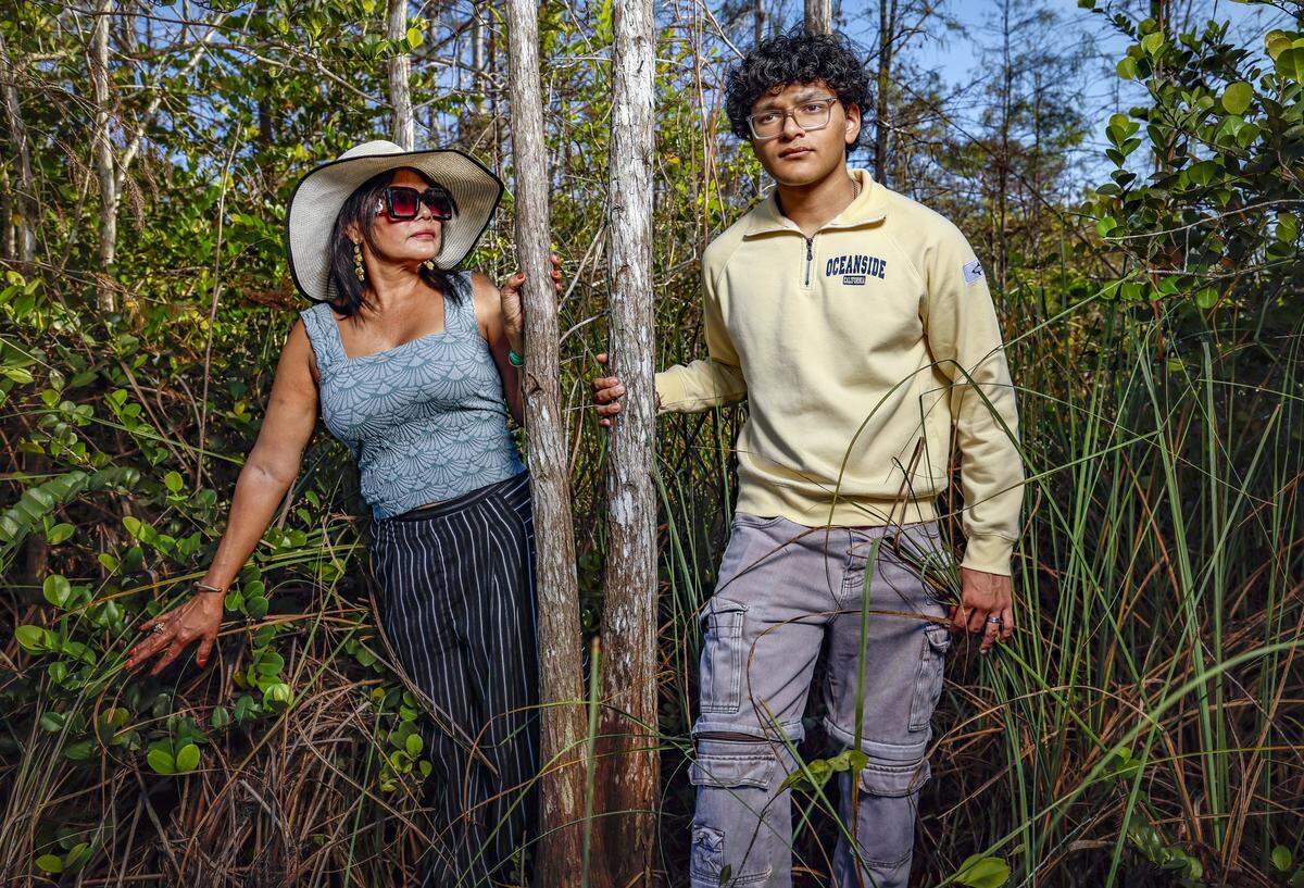 Donna Charles stands with her son Randy Nazir, 17, in the swamp across the street from the front entrance of Alligator Alcatraz, on Wednesday, November 19, 2025. Nazir, with the support of his mother, started a fundraiser on a GoFundMe page called Migrants Hope. Alligator Alcatraz is located at Dade-Collier Training and Transition Airport inside Big Cypress National Preserve in Ochopee, Florida.