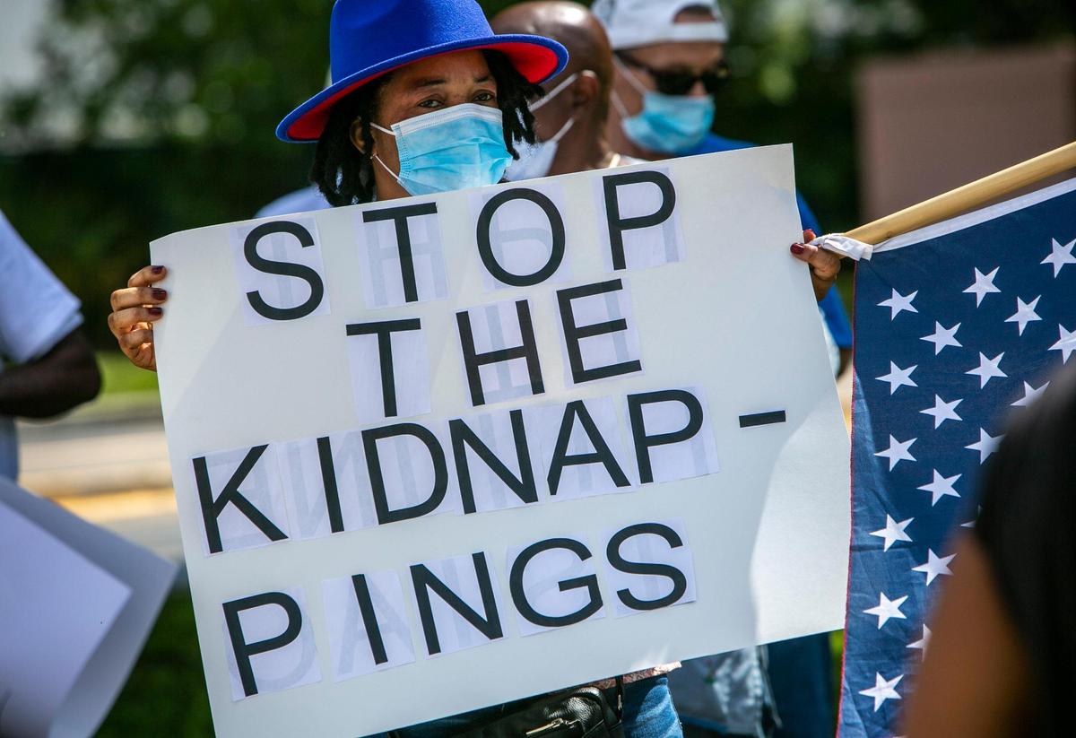 A protester holds a sign in front of the entrance to the Broward Transitional Center located at 3900 N Powerline Road in Pompano Beach, Florida. Family Action Network Movement, elected officials and community leaders gathered outside the Broward Transitional Center in Pompano Beach calling for the Biden Administration to reevaluate the current conditions of Haiti and urgently re-designate TPS for undocumented Haitian nationals living in the United States.