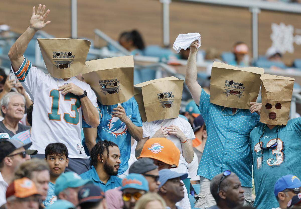 Miami Dolphins fans wear paper bags over their heads during the second half of their NFL football game against the Los Angeles Chargers at Hard Rock Stadium in Miami Gardens, FL, on Sunday, October 12, 2025. 