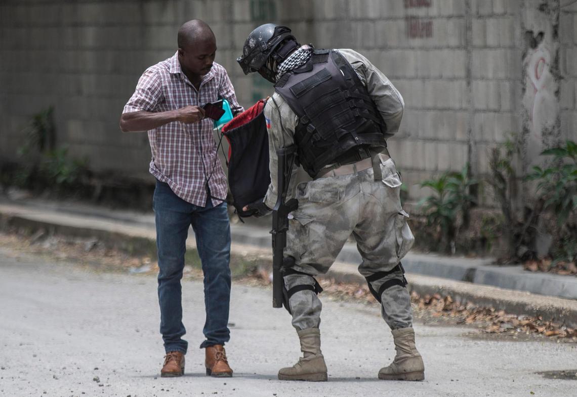 A police officer searches the bag of a resident during an anti-gang operation in Croix-des-Missions north of Port-au-Prince, Haiti, Thursday, April 28, 2022. (AP Photo/Odelyn Joseph)