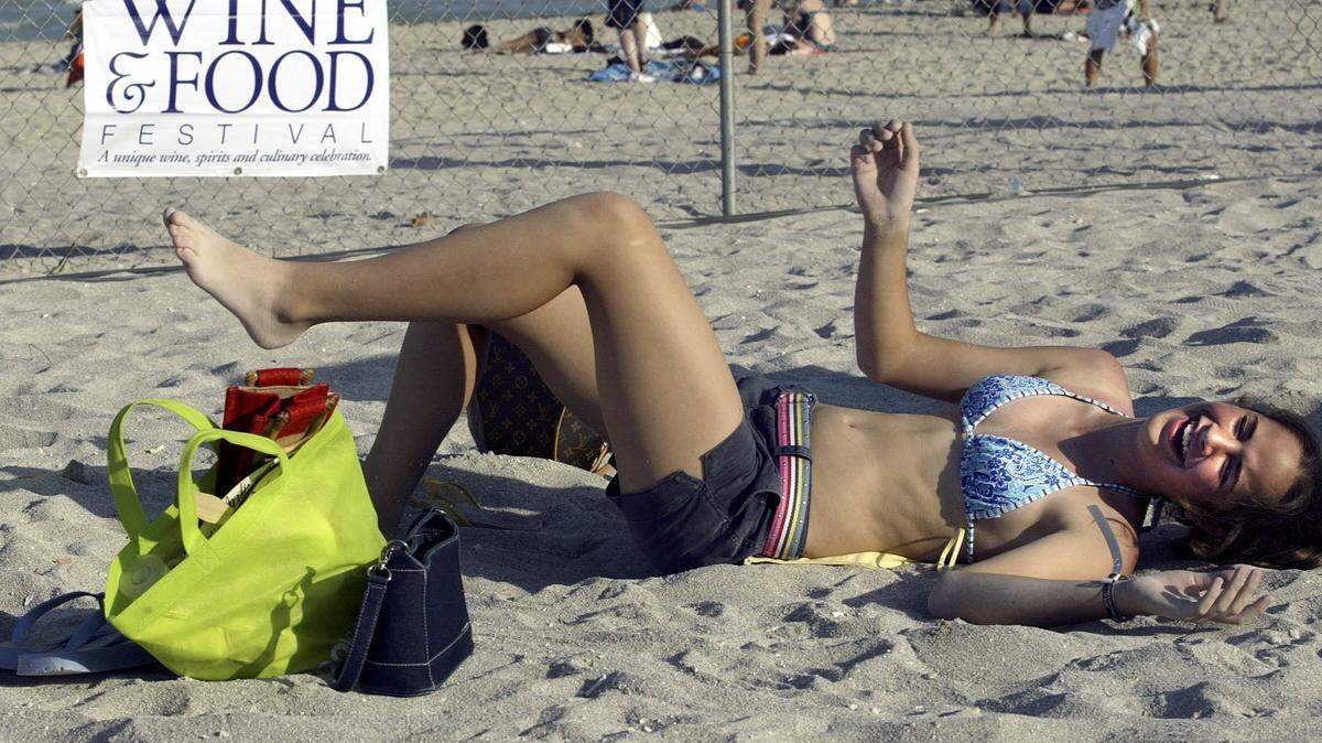 In 2004, Monica Fernandez, 12, of Miami enjoys a laugh and a rest from a day spent scarfing down exotic food and drinks at the South Beach Wine & Food Festival Grand Tasting.