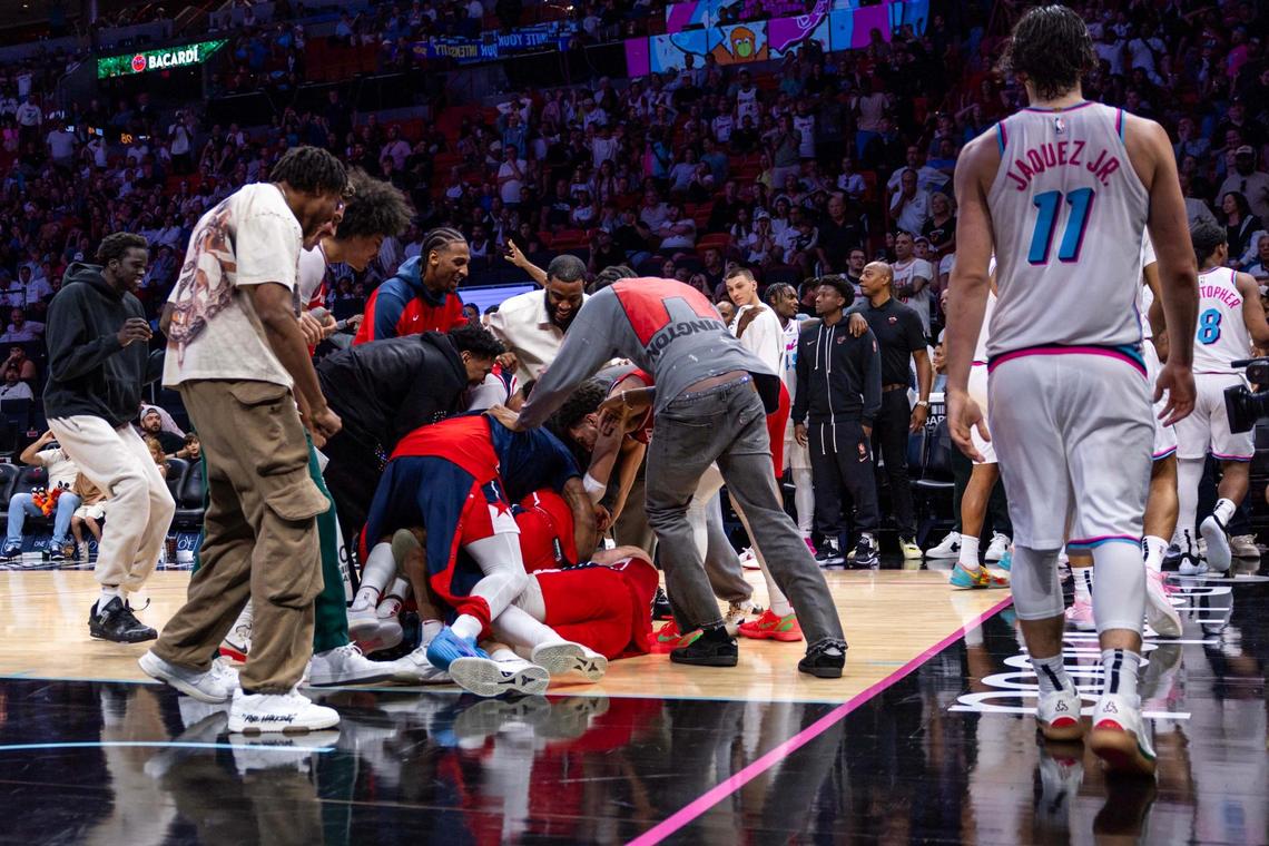 Washington Wizards players dog pile on teammate Bub Carrington (8) after scoring a buzzer-beater game-winner over Miami Heat guard Jaime Jaquez Jr. (11) to defeat the Heat 119-118 during the second half of an NBA game at Kaseya Center on Sunday, April 13, 2025, in Miami, Fla.