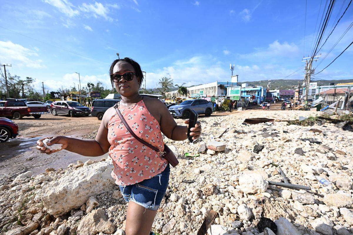 A woman walks on rubble left following the passage of Hurricane Melissa following the passage of Hurricane Melissa, in Santa Cruz, St Elizabeth, Jamaica on October 29, 2025. Hurricane Melissa ripped up trees and knocked out power after making landfall in Jamaica on October 28, 2025 as one of the most powerful hurricanes on record, inundating the island nation with rains that threaten flash floods and landslides. 