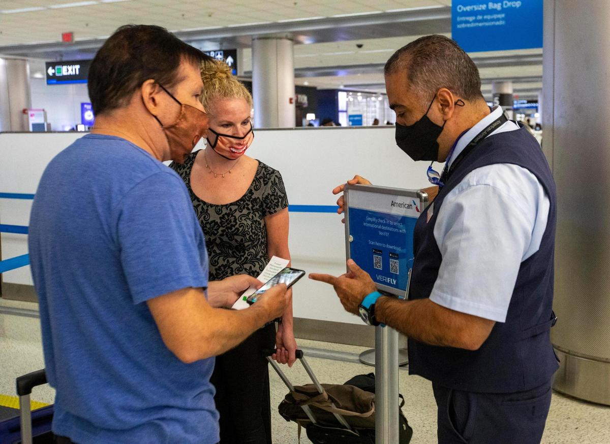 Canadian citizens Patty and Greg Miller speak with an American Airlines employee before checking in, using VeriFLY, a smartphone app that lets people upload documentation proof of negative COVID test or vaccine proof, before their international flight from Miami International Airport in Miami, Florida, on Monday, June 7, 2021.