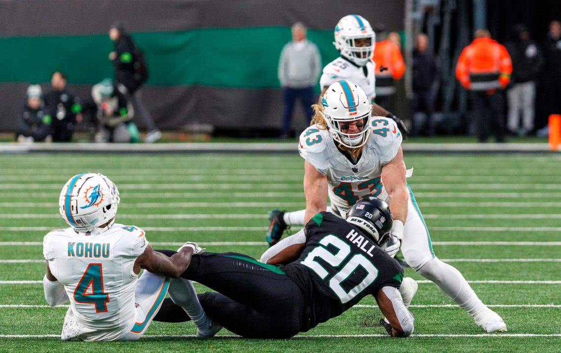 Miami Dolphins linebacker Andrew Van Ginkel (43) and Dolphins cornerback Kader Kohou (4) tackle New York Jets running back Breece Hall (20) during second quarter of an NFL football game at MetLife Stadium on Friday, Nov. 24, 2023 in East Rutherford, New Jersey.