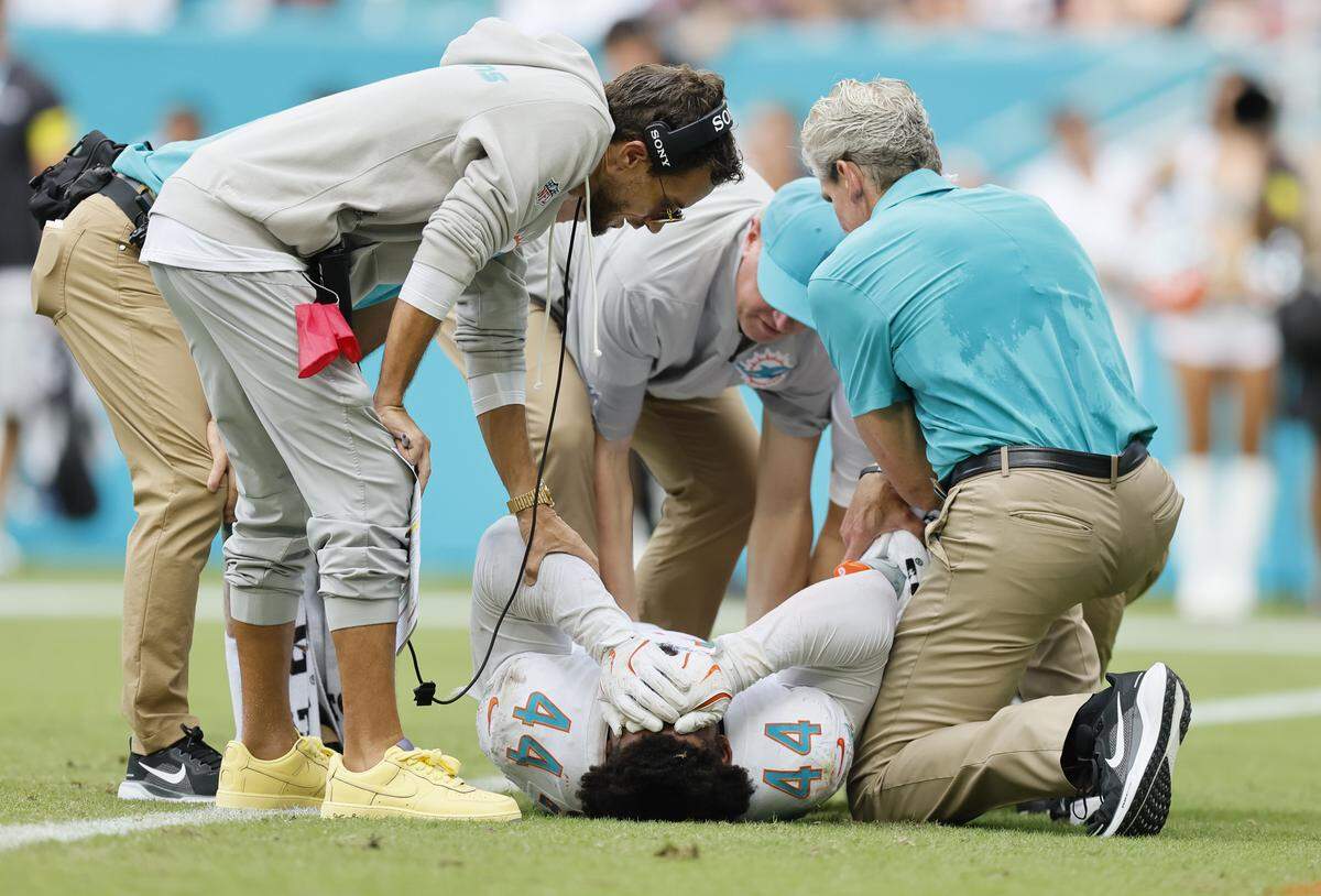 Miami Dolphins coach Mike McDaniel checks on linebacker Chop Robinson (44) after a hit against the New England Patriots in the NFL football game at Hard Rock Stadium in Miami Gardens, Florida, on Sunday, September 14, 2025.