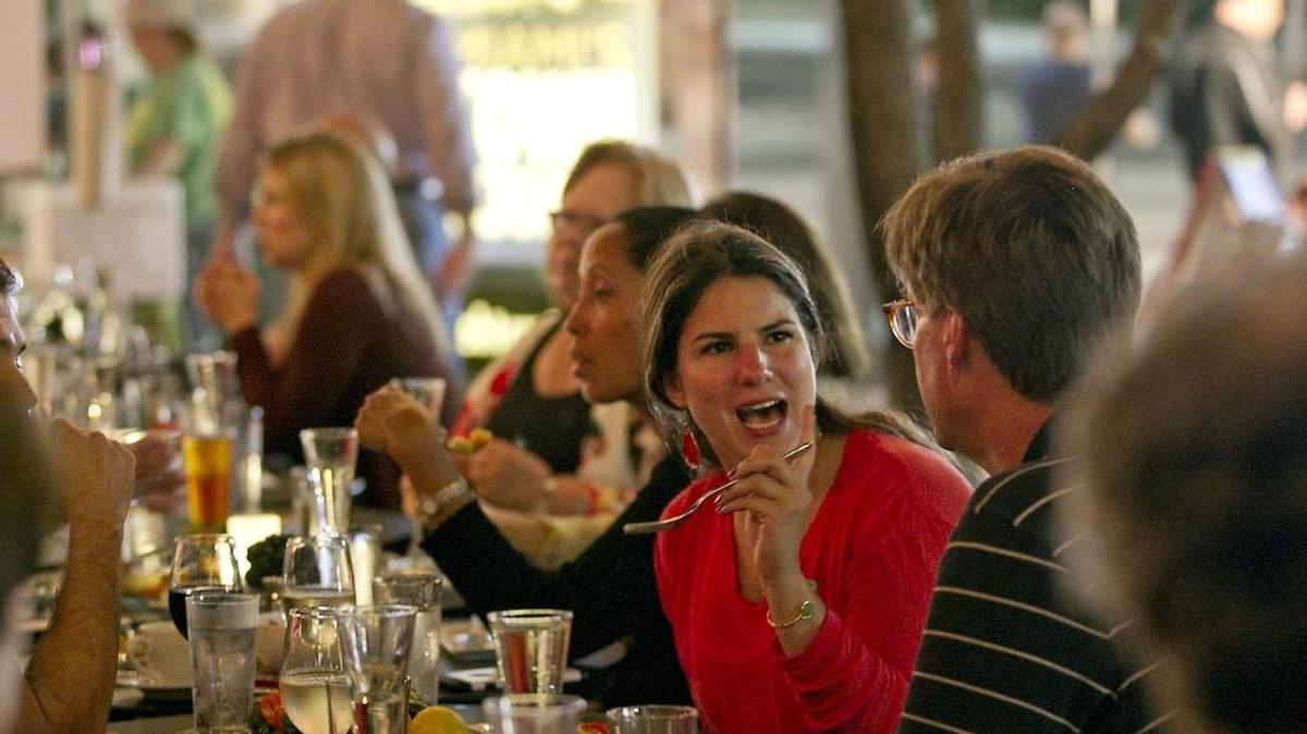 Luisa Marques dos Santos (in red) of Miami enjoys dinner and conversation at the Café at Books & Books on Monday Feb. 22, 2016. The cafe and chef Allen Susser host a family-style, five-course vegetarian meal in the plaza outside the Adrienne Arsht Center every Monday night.
