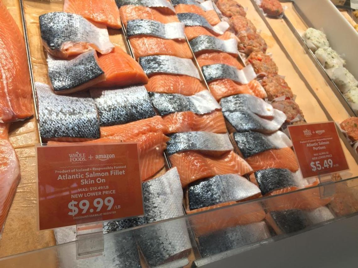 Signs co-branded Whole Foods and Amazon noted previous and new, lower prices on many of those items, including farm-raised salmon.