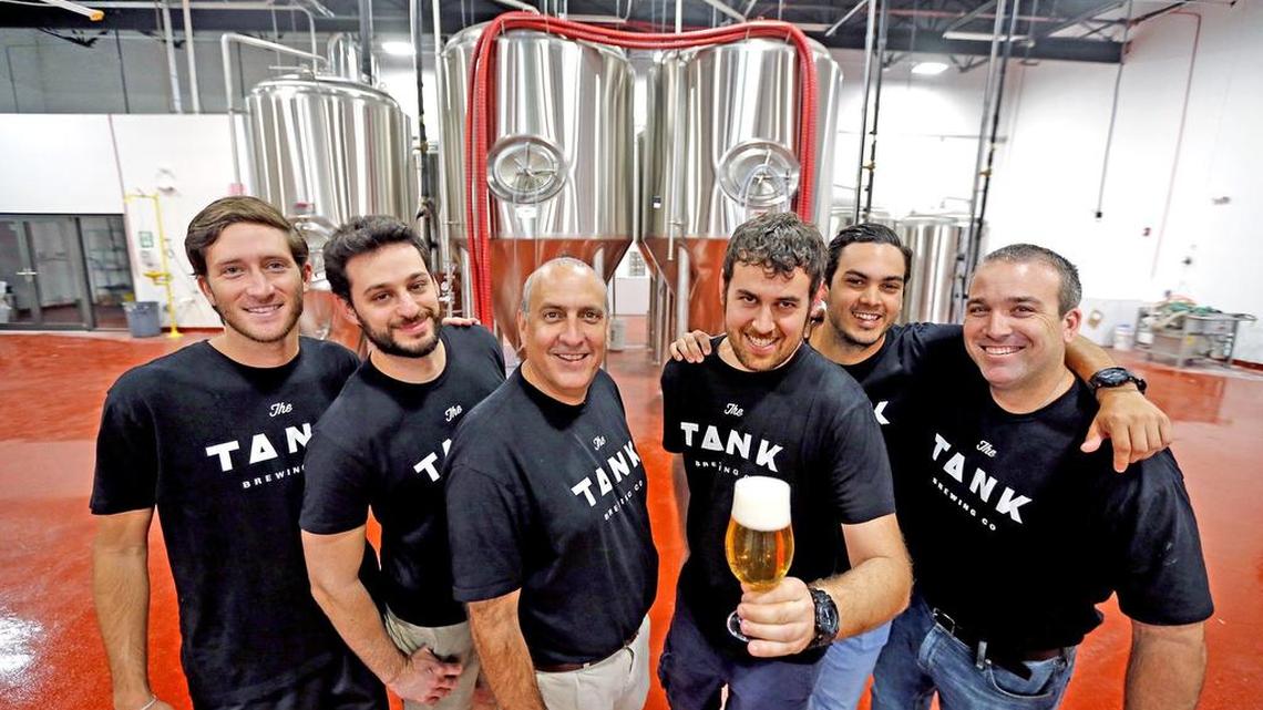 Owner Carlos Padron, 50, left-center, and Matthew Weintraub, 27, right-center, with their crew at the The Tank Brewing Company. The company was founded by cigar aficionado Padron and young head brewer Weintraub, formerly of FIU’s brewing program.