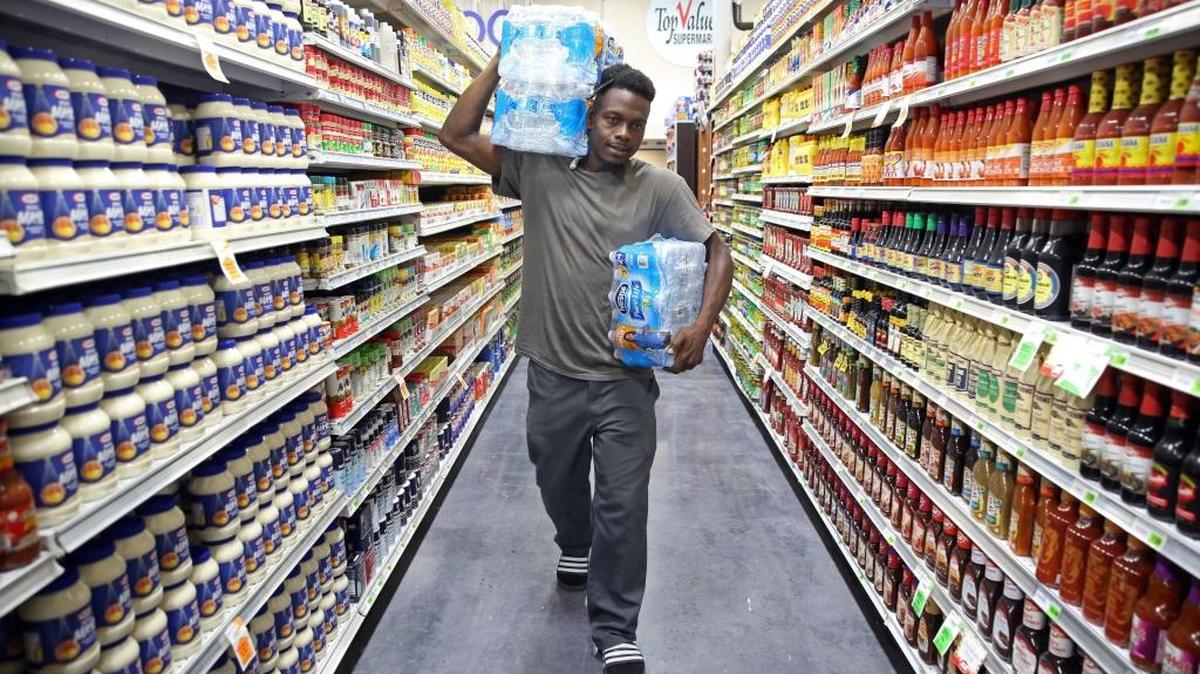 Top Value Supermarket, the first supermarket in years to open in the food desert that is Overtown today, had its grand opening on Wednesday, Oct. 5, 2016. The store opened just as residents were preparing for the effects of Hurricane Matthew. Overtown resident, Abdulah Dobey, 34, carries 3 cases of water through the aisles as he stocks up on supplies for himself and his daughters in preparation for the storm.