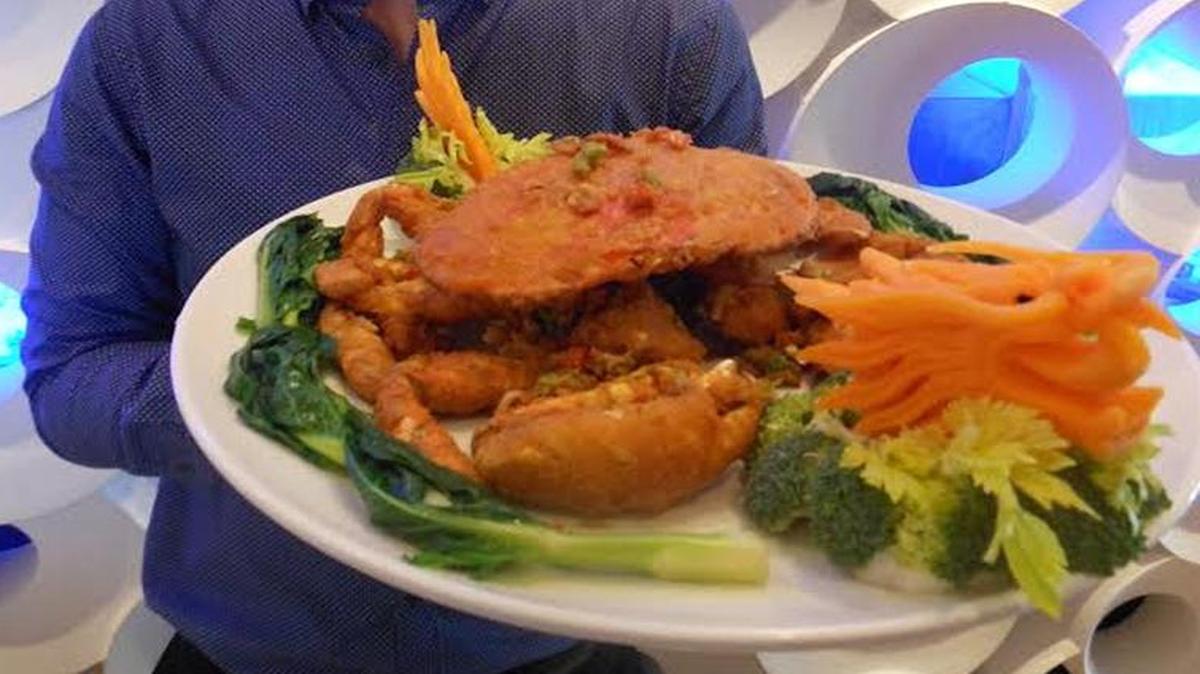 Manager Filbert ‘Fil’ Ip with Dungeness crab with a carrot dragon by the live seafood tanks at Gold Marquess Fine Chinese Cuisine