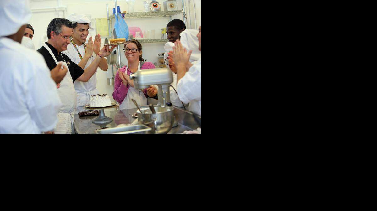 
Former Publix bakery manager Pedro Diaz holds up a cake as students Bryan Tomlinson, 26, Sophia Cruz, 21, and others clap during the adult baking and pastry arts program at the J.R.E. Lee Education Center for special needs adults.
