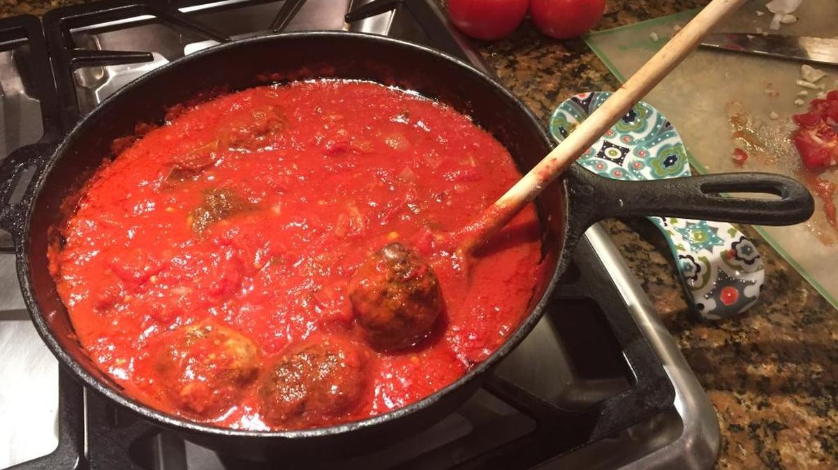 Use a cast-iron skillet to sear the meatballs. They finish cooking in tomato sauce.