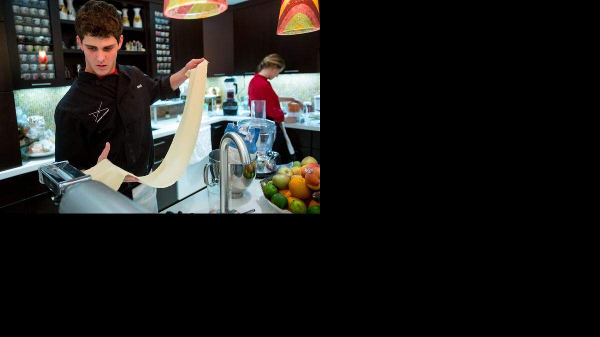 
David Lanster rolls out pasta dough while Kelly Moran works on a purée for a recent dinner they cooked. Their guests pay for their meals by donating to Common Threads, David and Kelly’s charity of choice.
