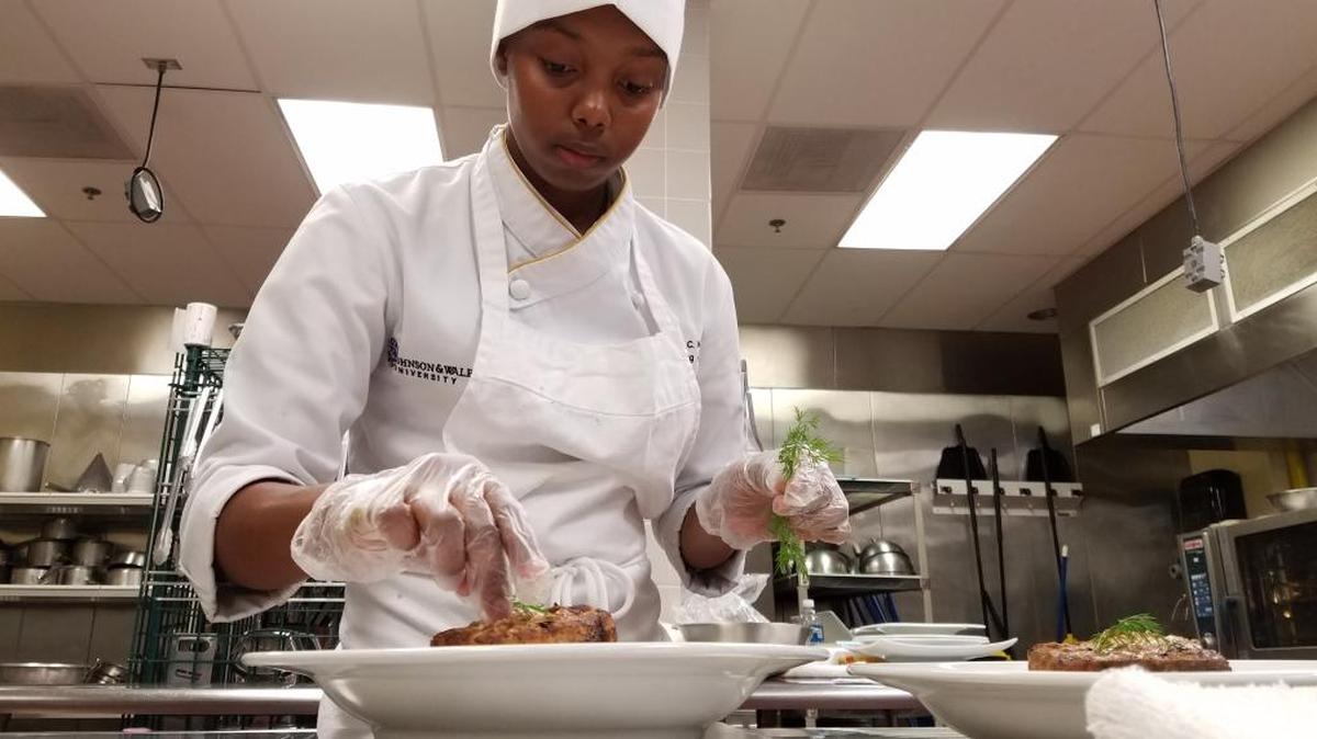 Nicole McDonald places a dill garnish atop her herb-crusted swordfish steaks.