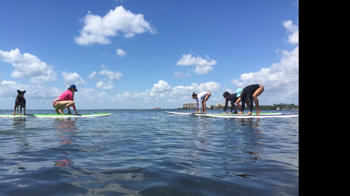 For Claudia Bustillos, left in pink, the water and the mind connect during a paddleboard yoga session because it is part of the meditation.
