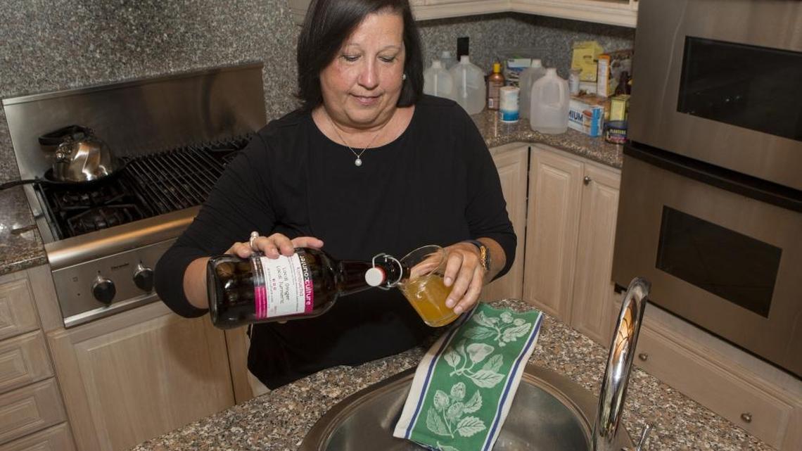Kim Reyes, 56, a patient at the Miami Cancer Institute at Baptist Health South Florida, prepares to drink kombucha, a fermented tea drink, at her Kendall home.