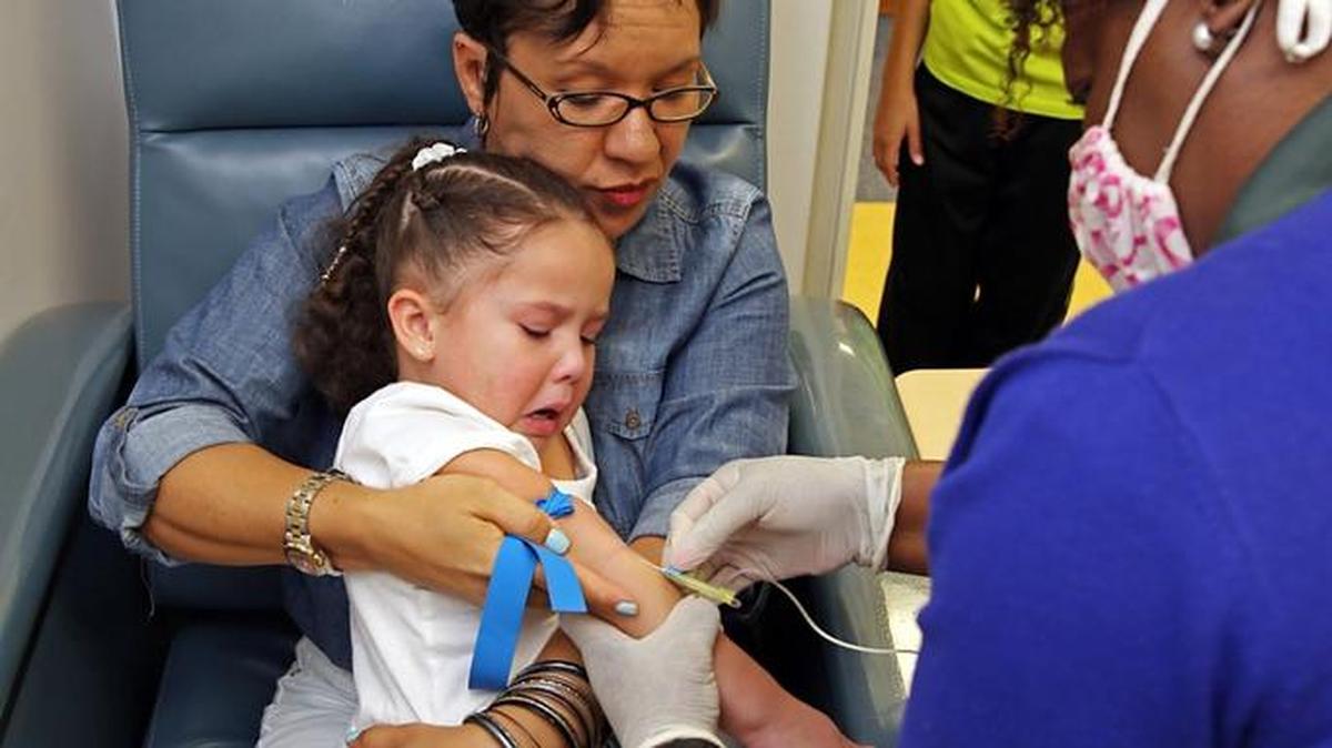 Olivia Lolo 3, is tested for diabetes as her mother, Stephanie Lolo, holds her while blood is drawn at the Memorial Healthcare System offices in Hollywood. Olivia's brother Enzo, 8, is in the doorway and has type 1 diabetes.