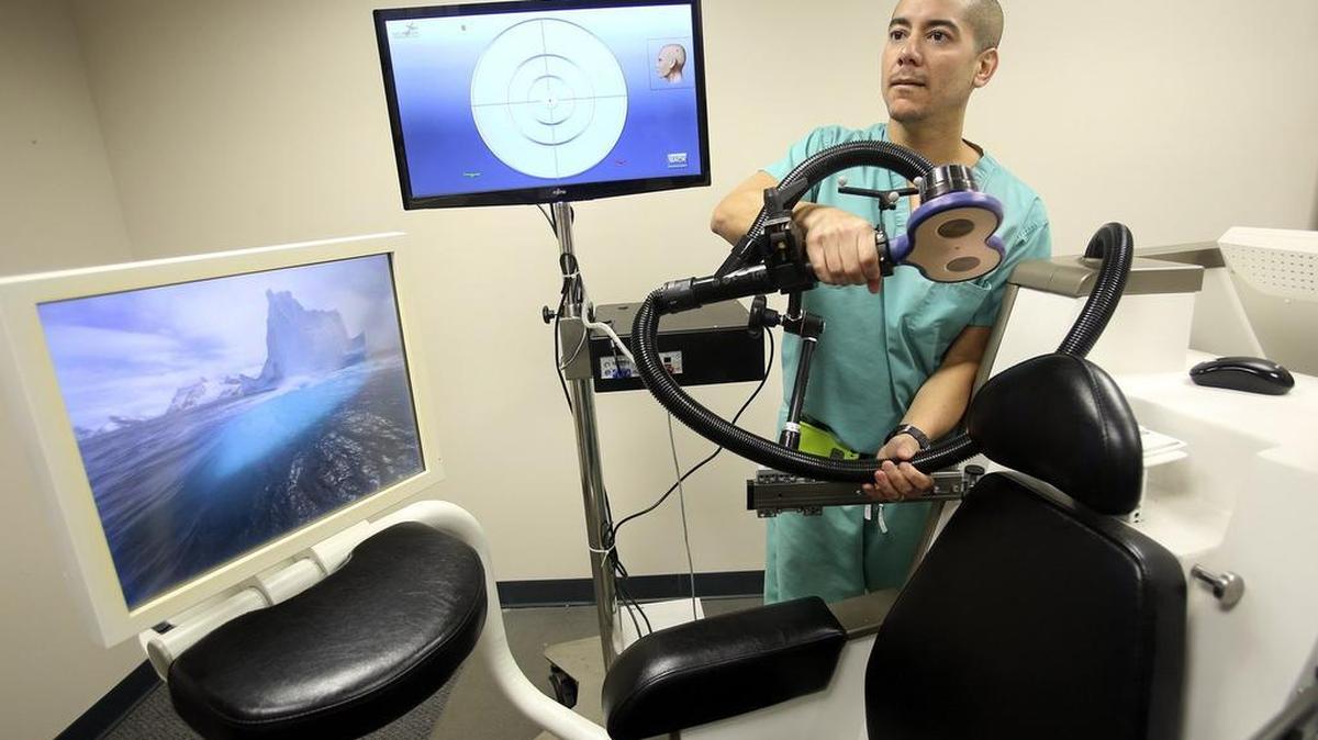 
Miami Jewish Health Systems has one of the largest set of clinical trials going on for memory issues and Alzheimer's research. On Friday, Aug. 14, 2015, clinical research coordinator Alex Gomez demonstrates how to adjust equipment used by people with Alzheimer's Disease or mild cognitive impairment. Neuronix is the company that created this chair/machine, which combines transcranial magnetic stimulation (TMS) with cognitive testing to help a patient's memory. 
