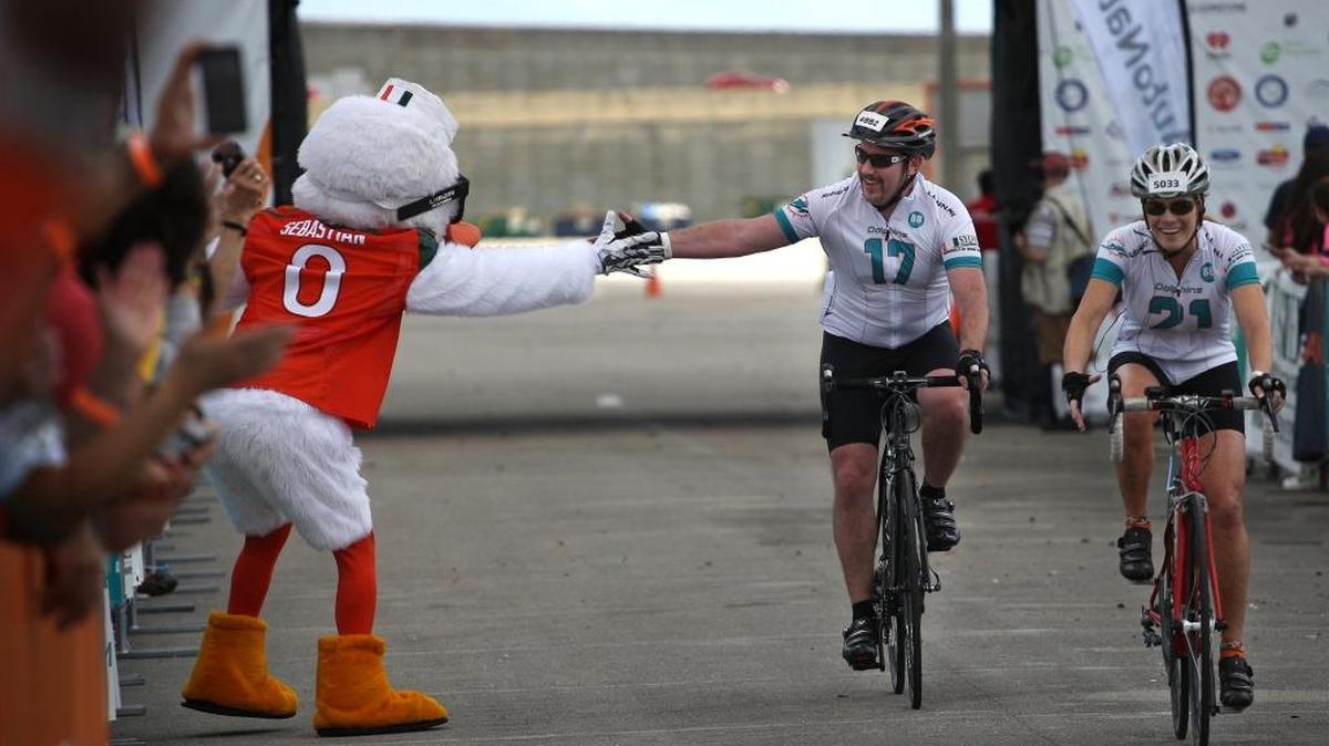 UM mascot, Sebastian, left, slaps a cyclist hand as he and fellow rider enter SunLife Stadium after some rode over 150 miles to raise money for research and a cure for cancer on during the 2014 Dolphins Cycling Challenge. This year’s challenge takes place on Feb. 20.