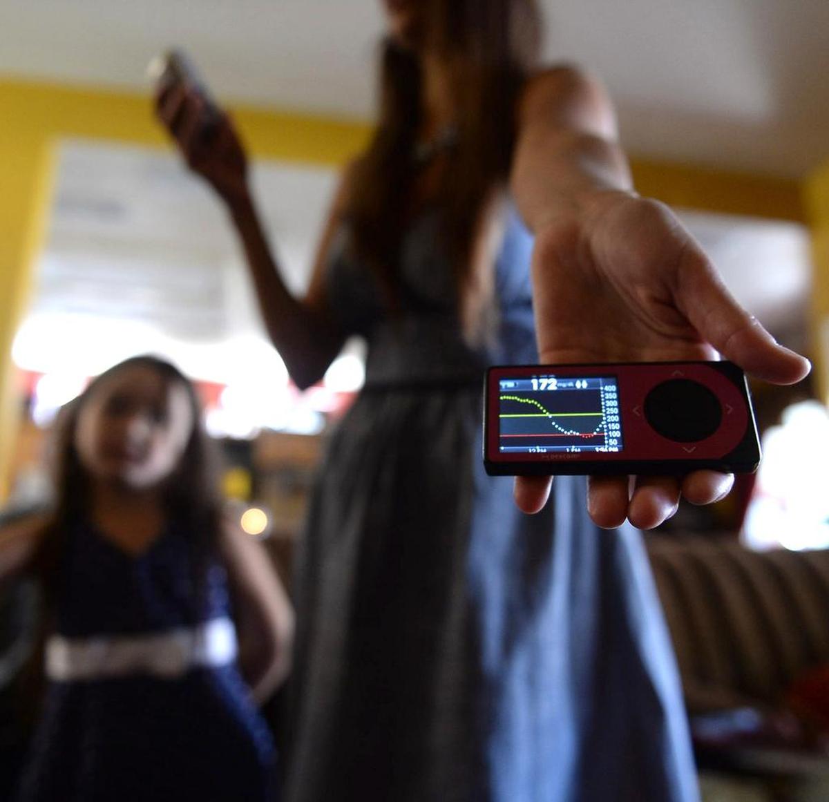 Shannon Briggs demonstrates a sensor device that automatically monitors critical body chemistry to keep her daughter’s diabetes in check on June 25, 2013. Lala, 6, has  type 1 diabetes.