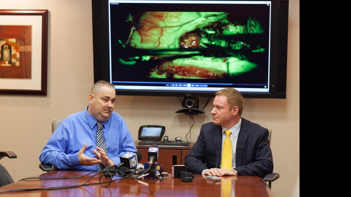 

The full scope: Shawn Monti, left, who was diagnosed with glioblastoma, discusses his surgery with Dr. Ricardo Komotar of UM’s Sylvester Comprehensive Cancer Center as a video of the operation plays in the background. 

