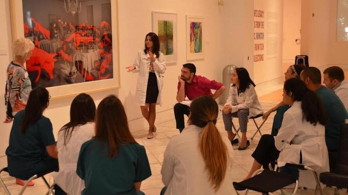 
DIFFERENT VIEW: Daphne Papathomas, a third-year UM medical student, leads a discussion of Sandy Skoglund's print, ‘Fox Games,’ at the Fine Art of Health Care workshop at the Lowe Art Museum. 
