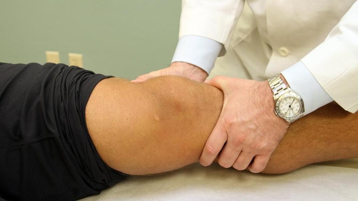 Lee Kaplan, M.D., chief of UHealth Sports Medicine, examines his patient Marc Megna, a former NFL player and currently a personal trainer, at the University of Miami Hospital on Tuesday, January 14, 2014. Megna had surgery on his knee to remove a meniscal tear.
