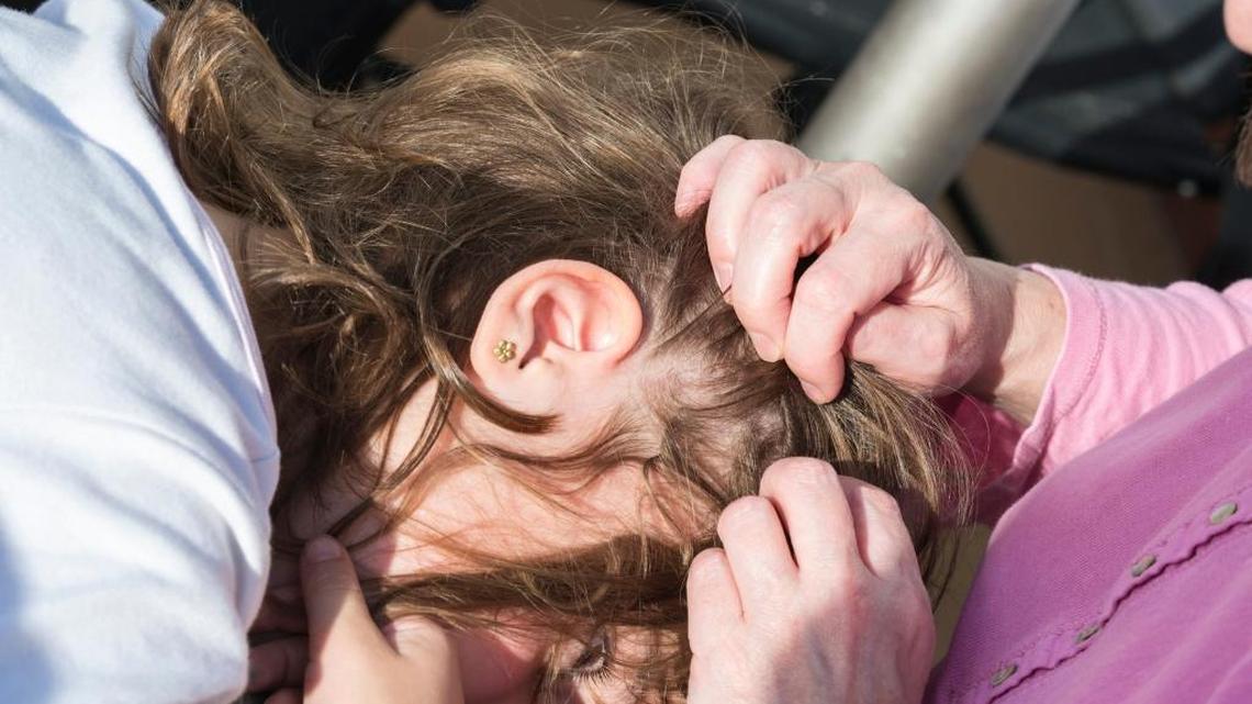 A mother examines her daughter for head lice.