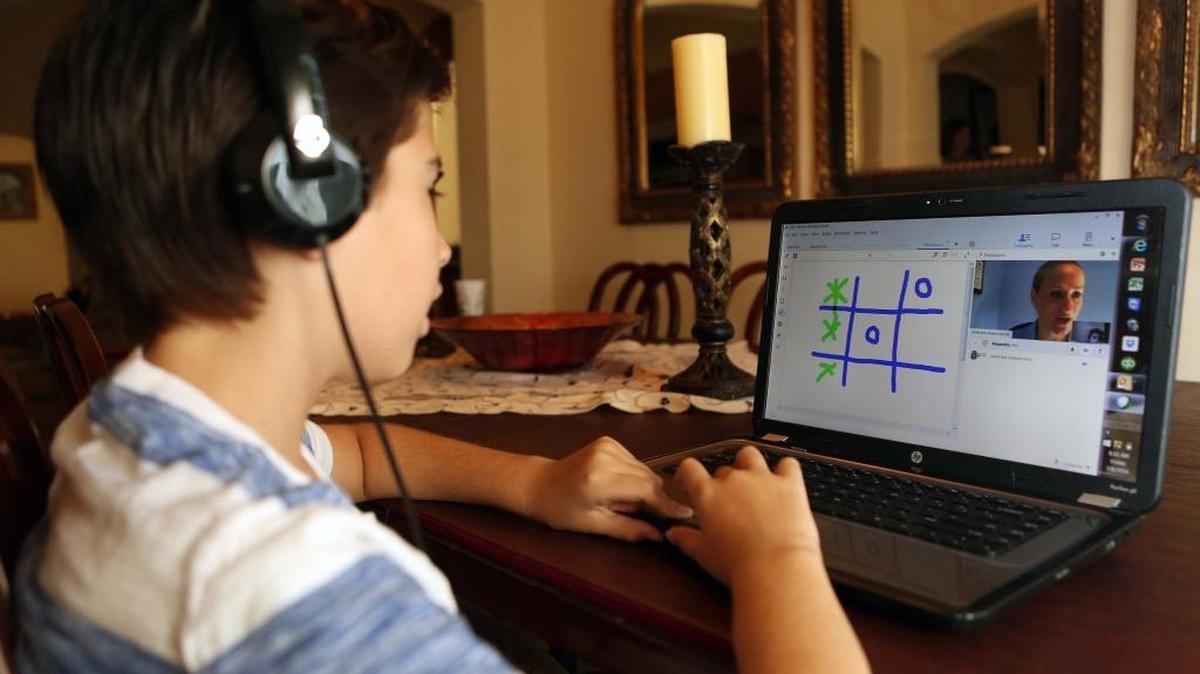 Alejandro Mijares works remotely from his home with his speech therapist through TeleSpeech. He wears earphones and sees his therapist via webcam while interacting with her through the computer screen.