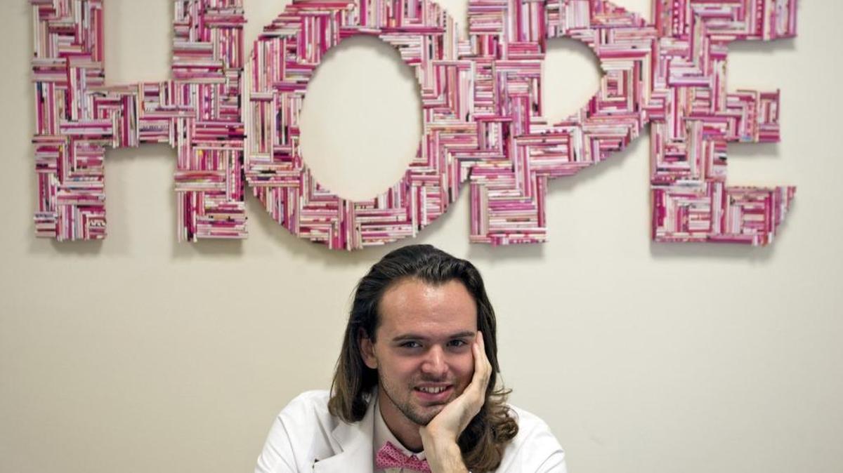 Joseph Burns, director of this year’s art exhibit by the Mammography Art Initiative, is photographed with a work called "Hope" by Aquarela Sabol currently displayed at the FIU Herbert Wertheim College of Medicine.