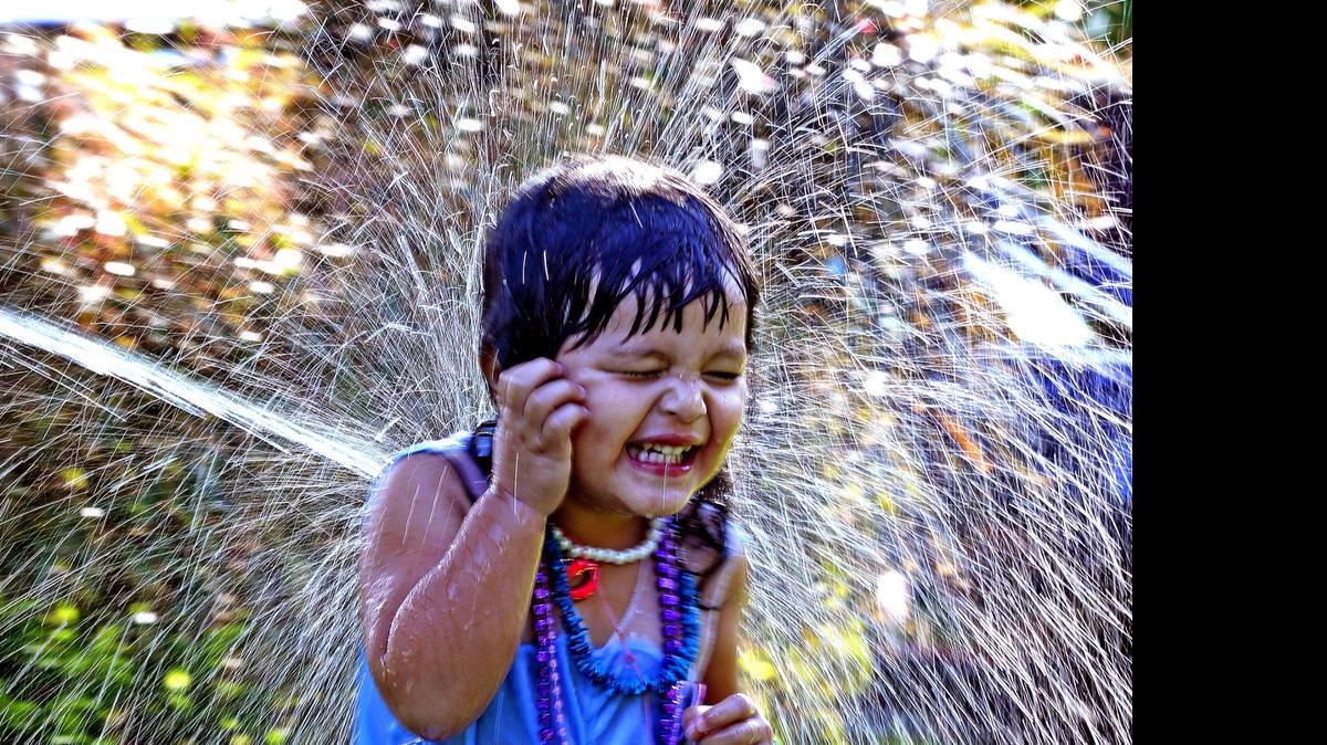 Bunica Sherman, 2, gets hit by a steam of water from a hose amid temperatures that hit the low 90s on Monday.  Now that summer is here, we're in a hot spell that will make it feel more than 100 this week.