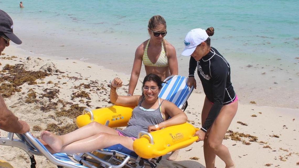 Volunteers lower Sabrina Cohen into the water on the floating chair.