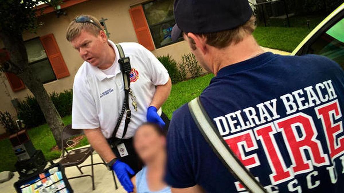 Delray Beach Fire Rescue Battalion Chief Ed Beardsley (center) and firefighter-paramedics treat a woman overdosing on heroin in Delray Beach on May 19, 2017. Neighbors say a car pulled up to a stop sign, pushed the woman out and drove away.