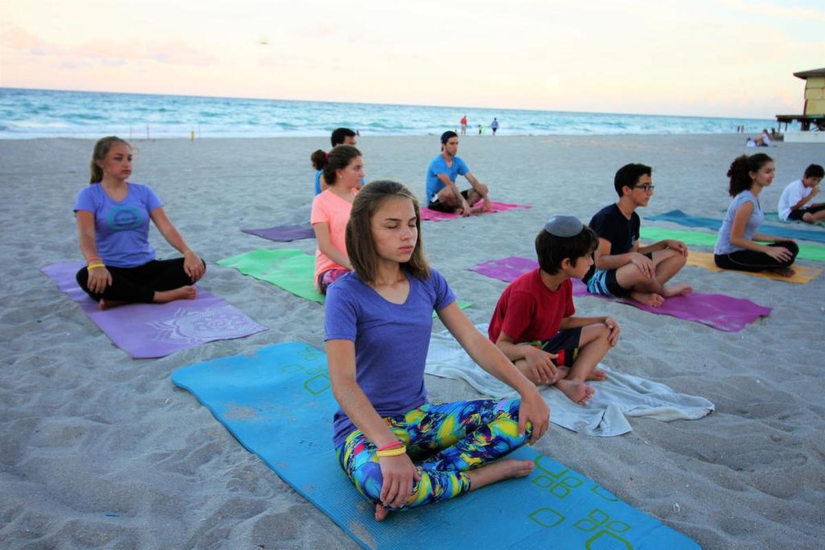 Sara Nagler, 13, in the foreground, meditates during a Hollywood Beach sunset yoga and meditation class.