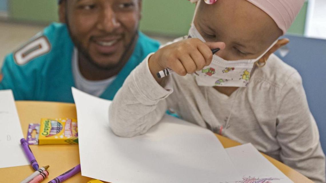 Brandon Gibson, one of two Miami Dolphins players who visited patients, their families and staff at alex’s place, colors with Salma Richani in December 2014at Sylvester Comprehensive Cancer Center. Alex's place is Sylvester’s pediatric oncology clinic. Funds raised from the Dolphins Cycling Challenge directly support pediatric oncology research.