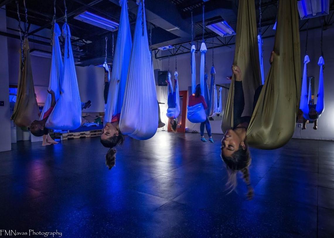Students hang in a “pouch” pose before flipping over into an inversion nicknamed the “chicken wing” at Stardust Fitness in Doral.
