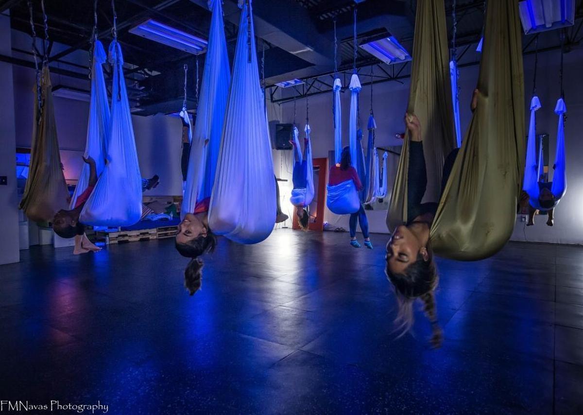 Students hang in a “pouch” pose before flipping over into an inversion nicknamed the “chicken wing” at Stardust Fitness in Doral.