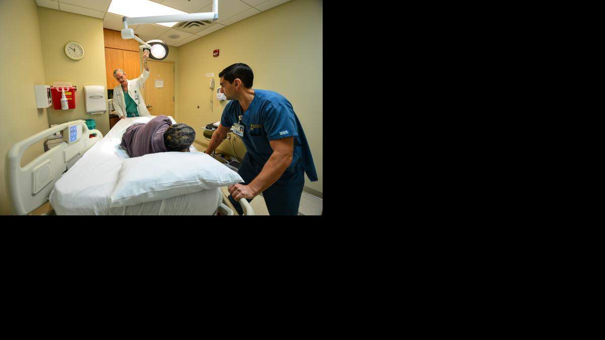 
A. Enrique Whittwell, M.D. of general surgery and medical director of South Miami Hospital's wound care division, along with Osvaldo Artigas, R.N., assess a patient, who declined to be identified, at South Miami Hospital.
