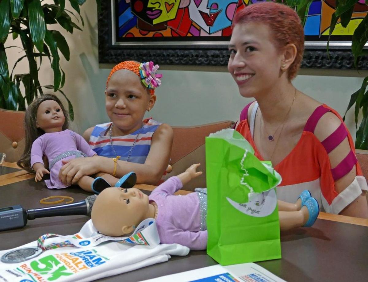 Georgina, a little girl with cancer, and Raquel Coronell, 17, who also had cancer, with bald American Girl dolls at Nicklaus Children’s Hospital on March 11, 2016.
