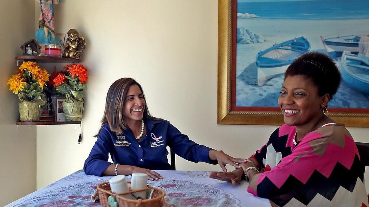 Maria Martinez, left, breast health navigator with the Herbert Wertheim College of Medicine at FIU, talks with Daisy Angulo, a breast-cancer survivor, at her home.