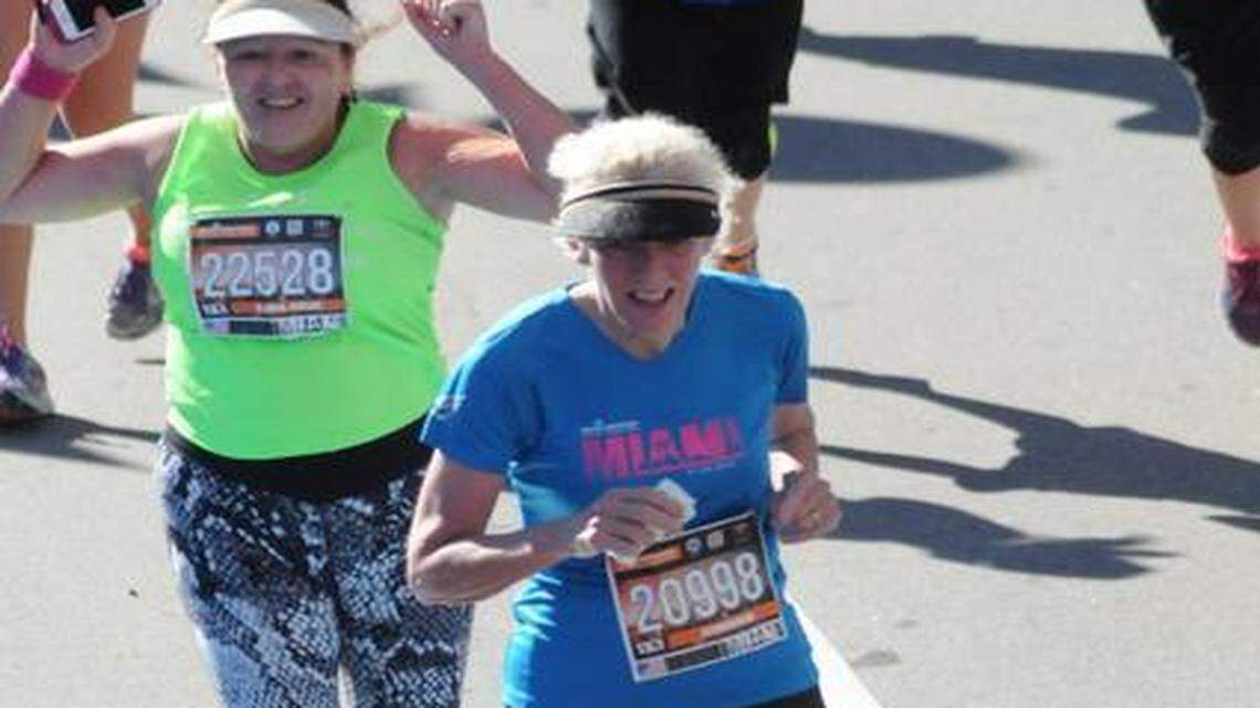 CROSSING THE FINISH LINE: Joan Chrissos, right, and Alina Cruz, in green shirt, cross the finish line together at the Miami Marathon. They ran the half marathon and are running partners, training through TeamFootWorks in South Miami.