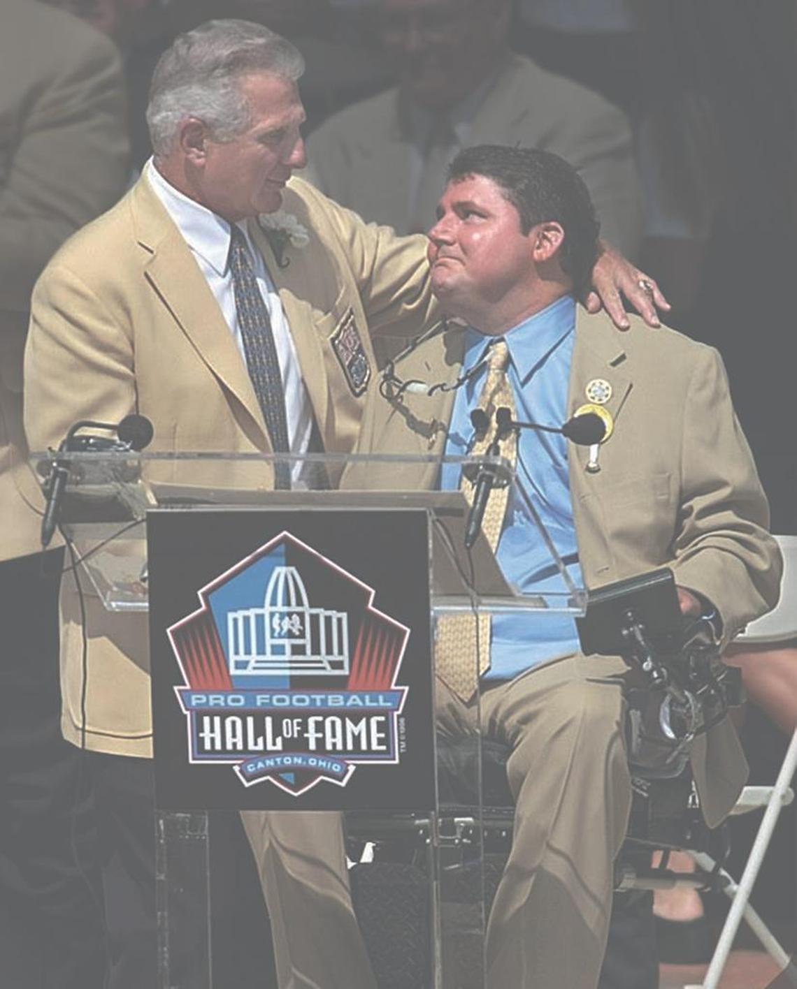 Former Dolphins player Nick Buoniconti and son Marc share a moment after Marc introduced his father during the 2001 Pro Football Hall of Fame induction ceremony.
