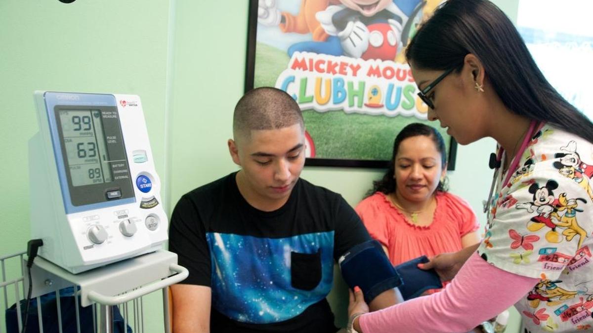 West Little Havana resident José Amaya, 14, gets his blood pressure measured by Gisselle Nogueira at Nicklaus Children’s Hospital as his mother, Sandra Amaya, looks on.